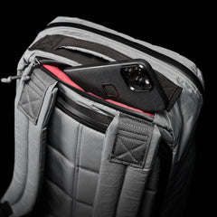 Gray GORUCK rucksack with padded straps and back panel, partially unzipped to reveal red interior lining and smartphone