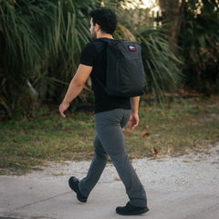 Man walking outdoors wearing GORUCK Xpac 21L black rucksack with an American flag patch
