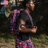 Man rucking outdoors with GORUCK USA flag camo backpack and shorts, fitness gear athlete