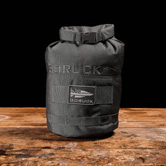 GORUCK grey rucking sandbag on rustic wooden table, durable tactical training gear