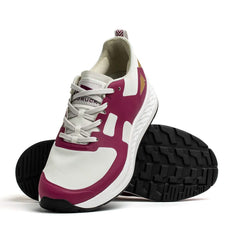 The Men's Rough Runner - Baton Rouge by GORUCK is showcased against a white backdrop, featuring a modern design. This athletic shoe displays magenta accents on the sides, a textured white sole, and black tread with gradient density. It is positioned to highlight both the side and sole views.