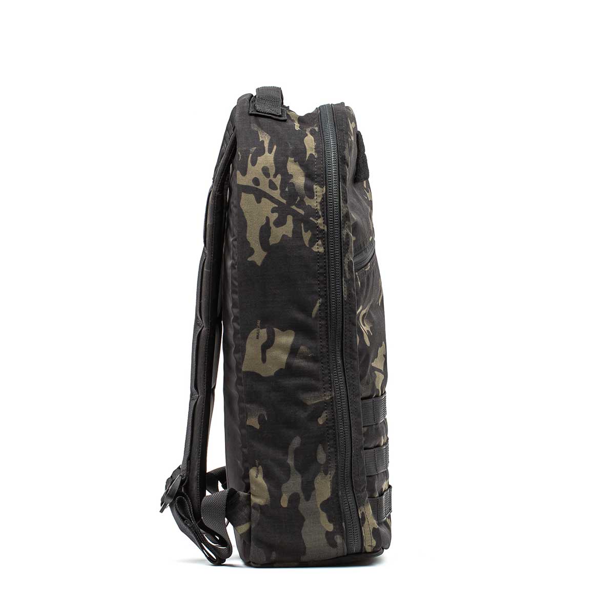 Side view of the Bullet Ruck Classic - Ballistic Nylon Cordura, a black and dark camo-patterned 15L daypack featuring a zipper and adjustable shoulder straps.