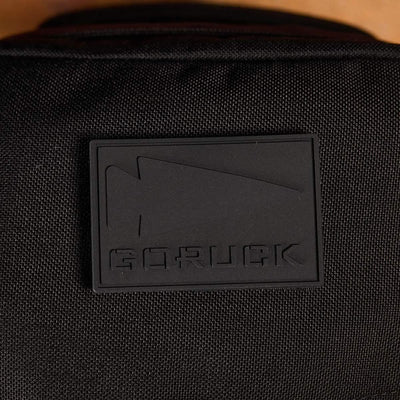 A detailed view of a PVC Patch from GORUCK, showcasing embossed text "GORUCK" accompanied by an arrow design. It is mounted on black material, possibly on a backpack or bag. This durable patch encapsulates the resilient and elegant spirit of Special Forces, reflecting the essence of the GORUCK spearhead.