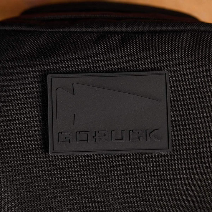 A detailed view of a PVC Patch from GORUCK, showcasing embossed text "GORUCK" accompanied by an arrow design. It is mounted on black material, possibly on a backpack or bag. This durable patch encapsulates the resilient and elegant spirit of Special Forces, reflecting the essence of the GORUCK spearhead.