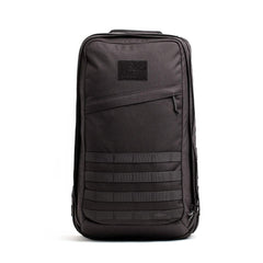 The GORUCK GR2 is a sleek black backpack with a minimalist rectangular design and a zippered front pocket. Ideal for travel, it features horizontal MOLLE straps at the bottom and a small patch area at the top, reminiscent of Special Forces style.