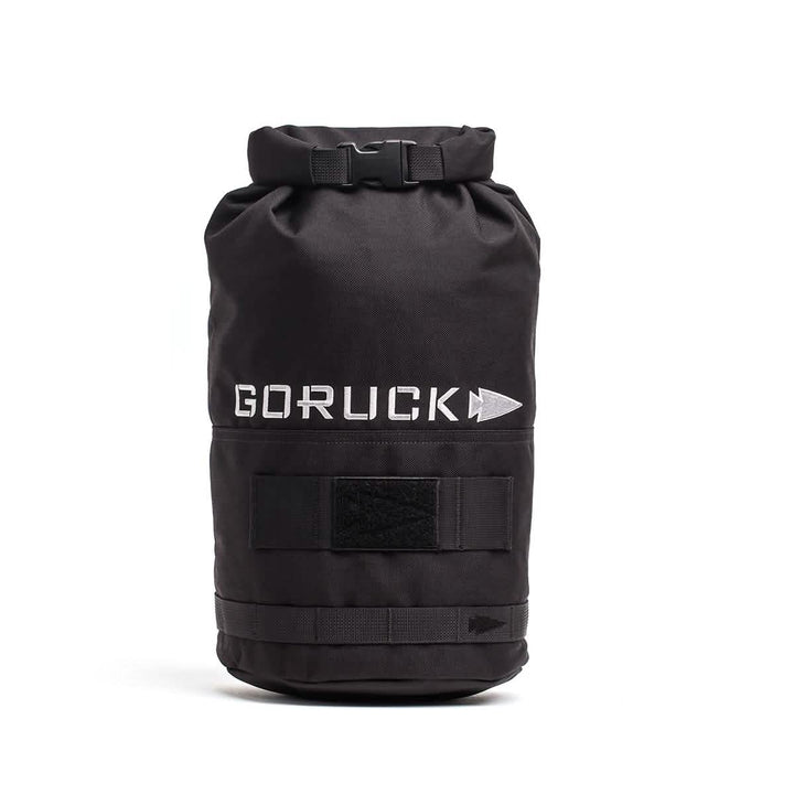 Introducing the Brick Bag (5-50 LBS) by GORUCK: A black rucksack featuring the GORUCK and arrow logo in white. This bag is designed with a roll-top closure, Velcro straps, and a durable exterior. Inspired by military gear, it functions as versatile training equipment or a dependable stuff sack for your adventures.