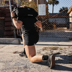 Person outdoors doing a lunge with a GORUCK rucksack on shoulders, wearing athletic gear