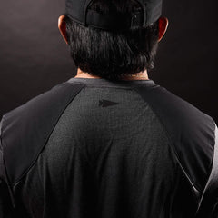 Back view of person wearing charcoal gray GORUCK shirt and black cap against dark background