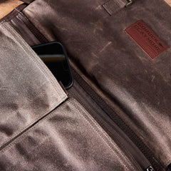 Close-up of the Heritage Claymore Sling Bag's interior, showcasing a phone partially tucked into a pocket. A visible label reads GORUCK. The rugged material evokes heritage durability and features a waxed canvas section with a zippered compartment.