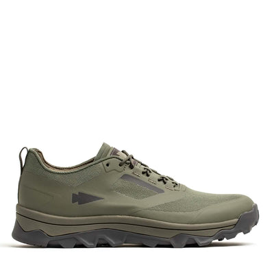 A GORUCK Mackall - Earth + Forged Iron trail shoe with a rugged triple compound outsole and streamlined design is displayed against a white background. Equipped with laces and a subtle arrow logo on the side, it seamlessly combines style and functionality, making it ideal for outdoor activities like rucking.