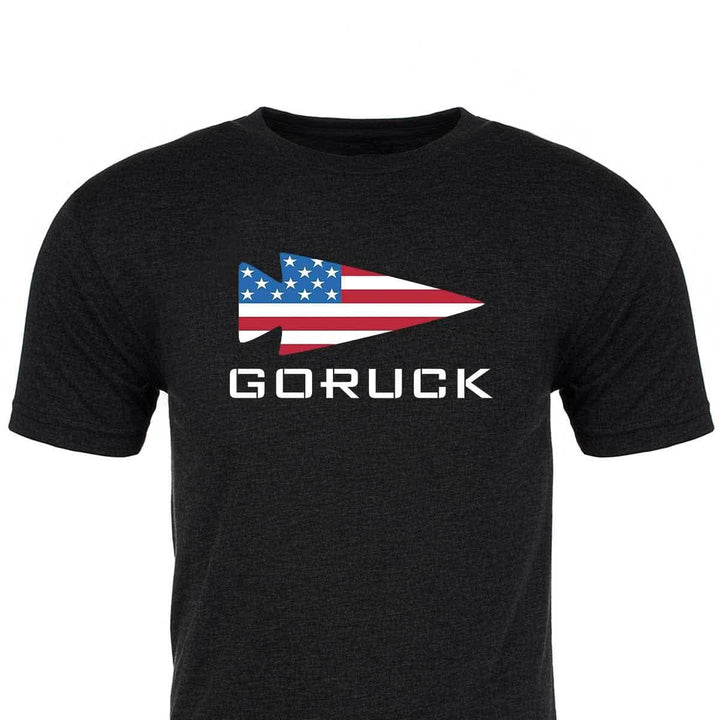 The GORUCK Flag Spearhead Tee - Tri-Blend features a black design with a GORUCK spearhead and US flag, "GORUCK" text below, and is crafted from premium tri-blend fabric for comfort and durability.