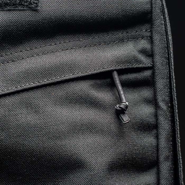 Close-up of a black fabric pocket with a zippered closure and a knotted zipper pull.
