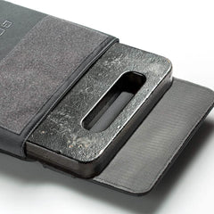 A black metal plate with a rectangular cutout is partially inserted into a gray GORUCK Ruck Plate Carrier 3.0 made from 1000D CORDURA fabric and featuring Velcro closures. The pouch is open, revealing the textured surface of the plate and the soft interior, ideal for Ruck Plate Carrier adventures.