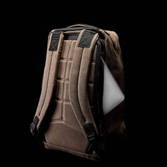 The GR1 USA - Heritage rucksack by GORUCK, featuring padded shoulder straps and a cushioned back, is showcased against a black background. A laptop is partially visible from an external pocket on the side of the rucksack.