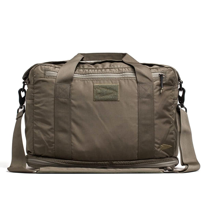 The Kit Bag with Shoe Compartment by GORUCK, constructed from Ripstop ROBIC® material, features a khaki green rectangular design reminiscent of a Special Forces Flight Bag. It includes multiple straps and zippers, along with a subtle logo patch on the front. For added convenience, it comes with a shoulder strap. Its rugged and utilitarian style makes it perfect for travel or daily use.