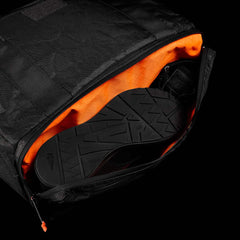 The Kit Bag x Carryology - Ultra Blaze is a sleek black backpack with an orange interior, unzipped to show black shoes inside—a stylish bag featuring a dedicated shoe compartment for organized travel.