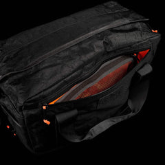 The Kit Bag x Carryology - Ultra Blaze is a black duffel with orange accents, shown partially unzipped to display its inner mesh pocket and tough UHMWPE fabric.