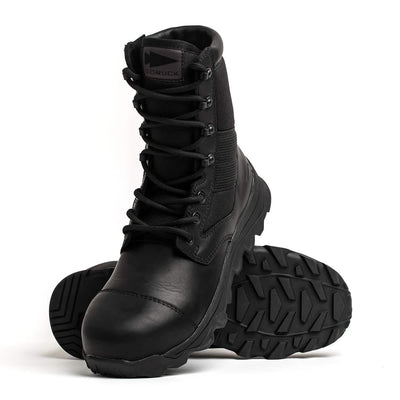 The MACV-2 Safety Boot - High Top, crafted by GORUCK to meet Special Forces standards, features rugged soles. One boot stands upright, while the other lies on its side, showcasing the thick tread pattern. The brand logo is visible on the tongue against a plain white background.