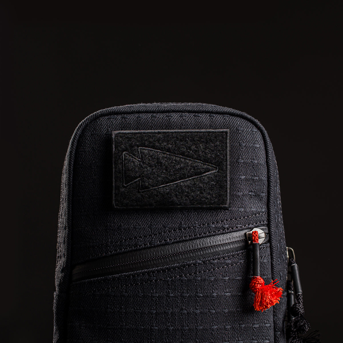 The GRenade x Carryology - GRXC2 Samurai 2.0 is a black tactical pouch with a diagonal zipper, waterproof design, a right-pointing arrow patch, and easy attachment to your tactical sling.