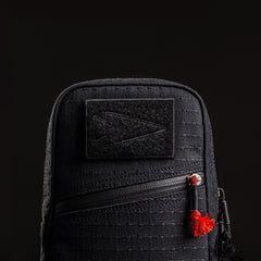 The GRenade x Carryology - GRXC2 Samurai 2.0 is a black tactical pouch with a diagonal zipper, waterproof design, a right-pointing arrow patch, and easy attachment to your tactical sling.