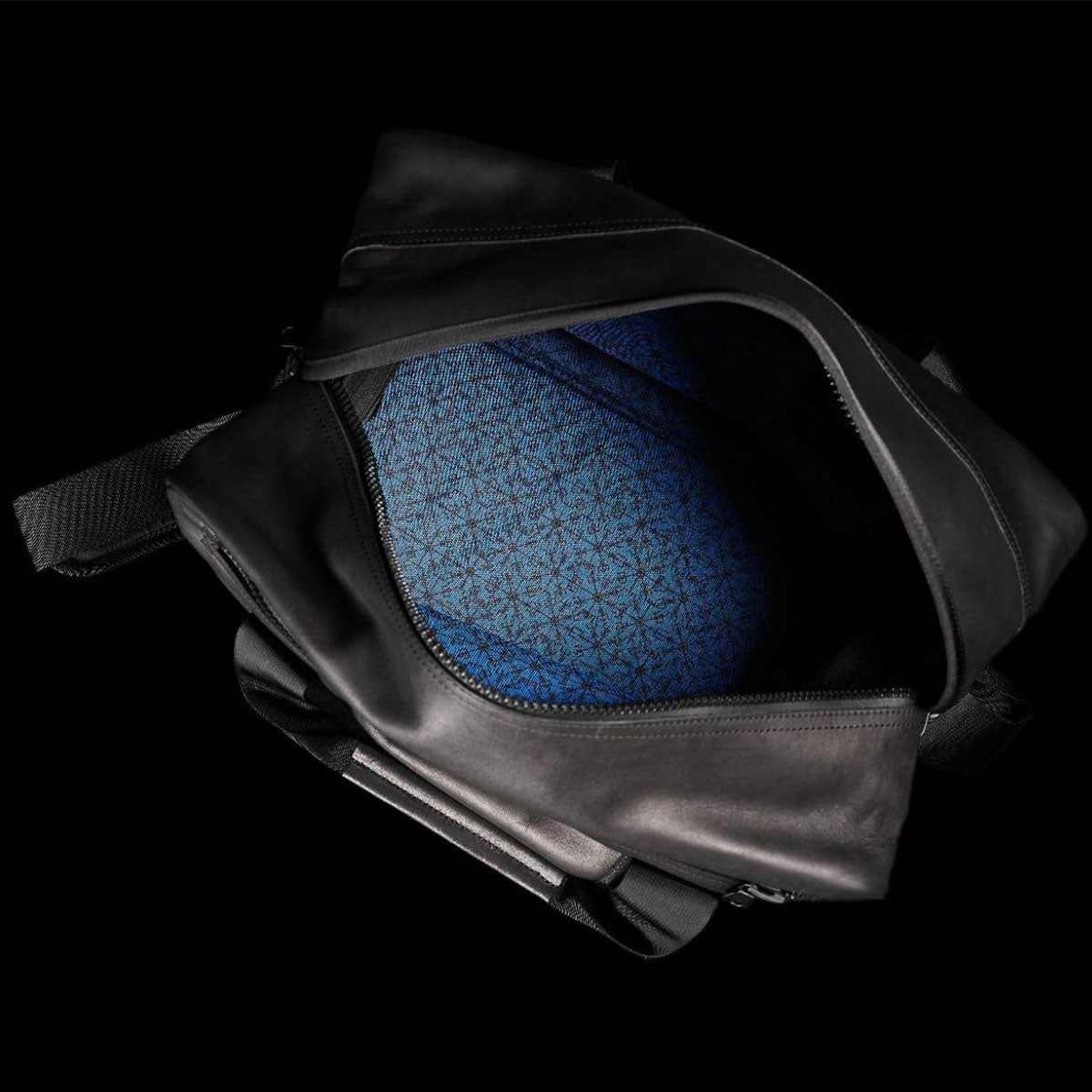 Open black bag with a blue, geometric-patterned interior on a black background.