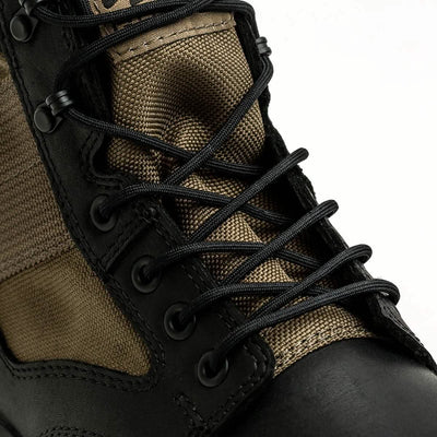 Close-up of a brown and black jungle boot featuring black laces. This MACV-2 - Mid Top - Origins model from GORUCK combines leather and fabric materials, highlighting the detailed craftsmanship favored by Special Forces, with meticulous emphasis on the laces and stitching.