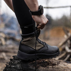 GORUCK rucking boot being laced outdoors on a log, tough hiking footwear for rugged terrain