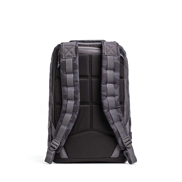 The GR1 rucksack in black and gray is shown from the back, featuring padded shoulder straps and a cushioned back panel, designed for exceptional durability to meet Special Forces standards.