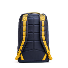 The GR1 rucksack, shown from the back in navy with padded yellow shoulder straps and a top handle, showcases quality American manufacturing.