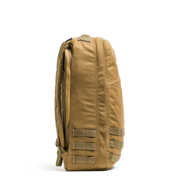 Side view of the tan GR1 rucksack featuring multiple straps and a zippered main compartment, inspired by Special Forces backpack design.