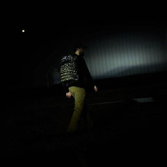 Walking at night, their Rucker 4.0 - Reflective Spearhead backpack glows, partially lighting the way as they move through the dark outdoors.
