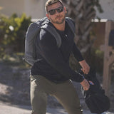 Man outdoors wearing GORUCK rucksack and sunglasses, training with weighted sandbag
