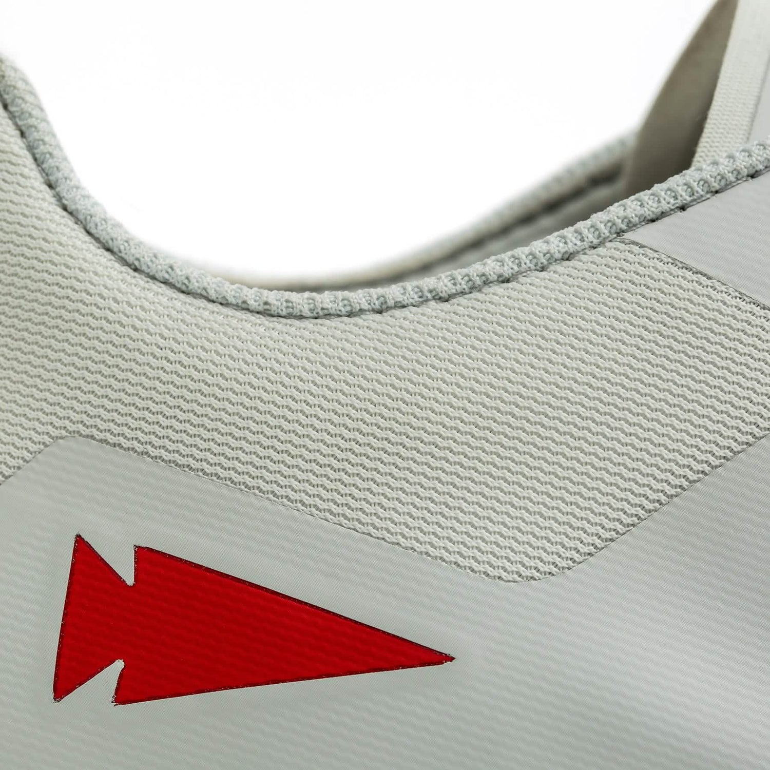 Close-up of the Women's Rough Runner sneaker in light grey with a red angular design on the side, by GORUCK. It features intricate stitching along the fabric edge and a Gradient Density EVA Midsole for enhanced cushioning, making it ideal for high mileage running without sacrificing style.