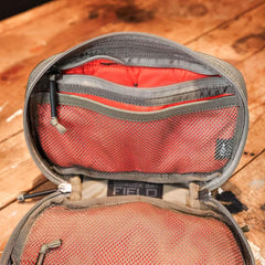 Open GORUCK GR1 Field pouch showing red interior with mesh pockets and durable stitching on wooden surface