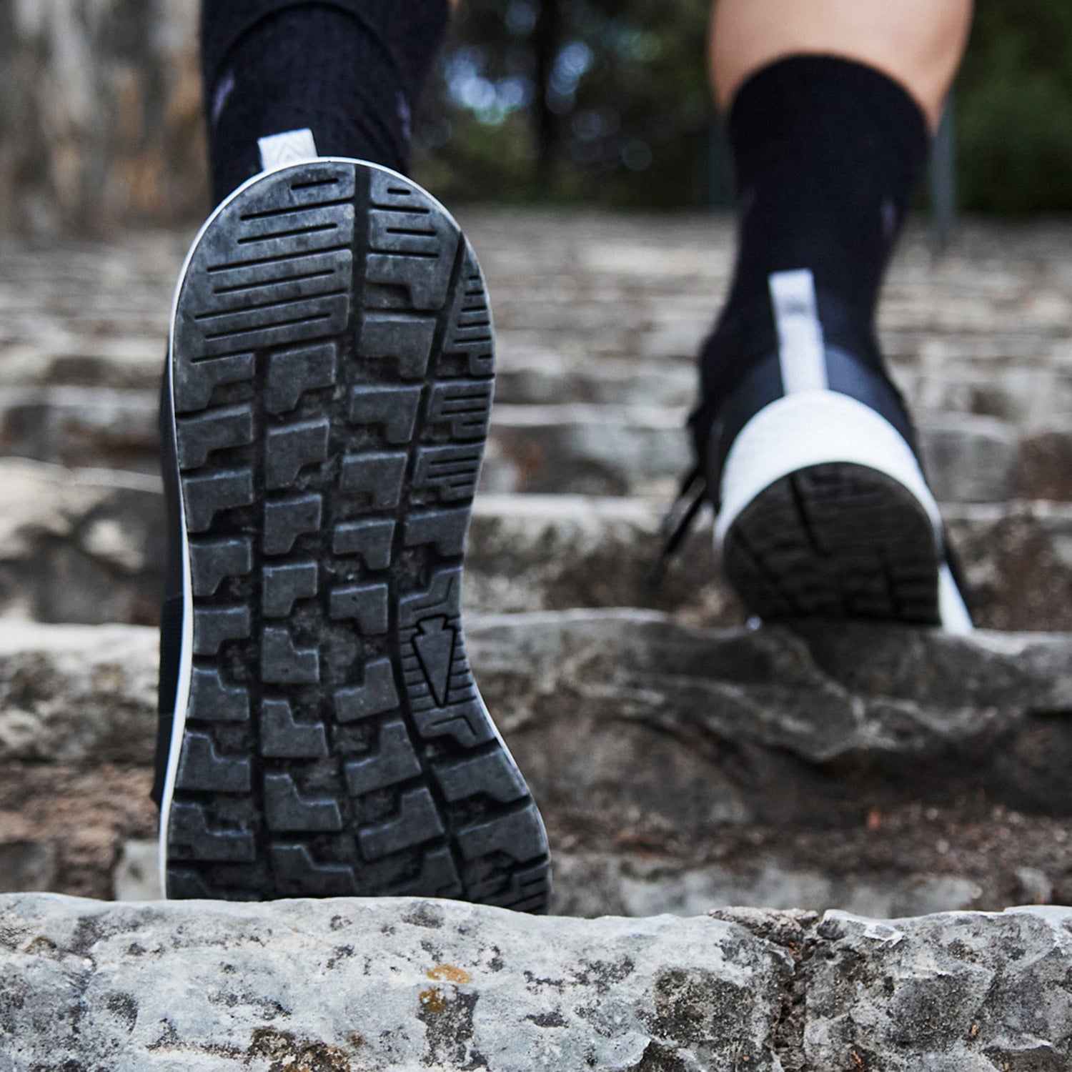 Close-up of a person walking up stone steps, focusing on the sole of their black shoe.