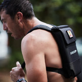 A man outdoors wearing the Ruck Plate Carrier 3.0 weighted backpack, with enhanced lumbar support visible on the strap.