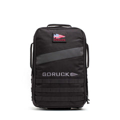 The Rucker 5.0 is a black GORUCK rucksack featuring an American flag patch, front handles, MOLLE webbing on the lower front, and built-in lumbar support for comfortable rucking.