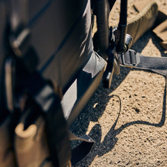 Close-up of the Rucker 5.0’s black straps and tan fabric with lumbar support, resting on sunlit rough concrete.