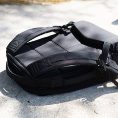 The Rucker 5.0 rests on a sunlit concrete surface, showcasing its straps and padded back panel with lumbar support.
