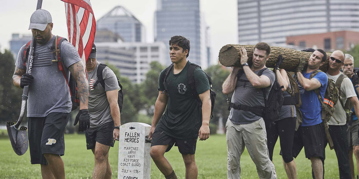 Group of people carrying a log and an American flag past a 