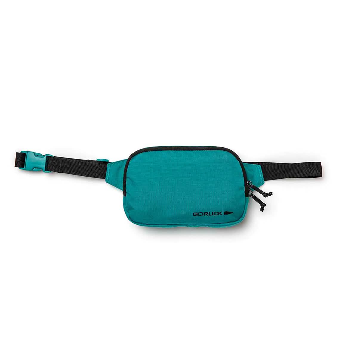 The Belt Bag, designed by GORUCK, is a teal waist pack featuring black zippers and an adjustable webbing strap with a matching teal buckle clasp. It is crafted to keep your gear organized and prominently displays the brand name GORUCK in bold black print on the lower right corner.