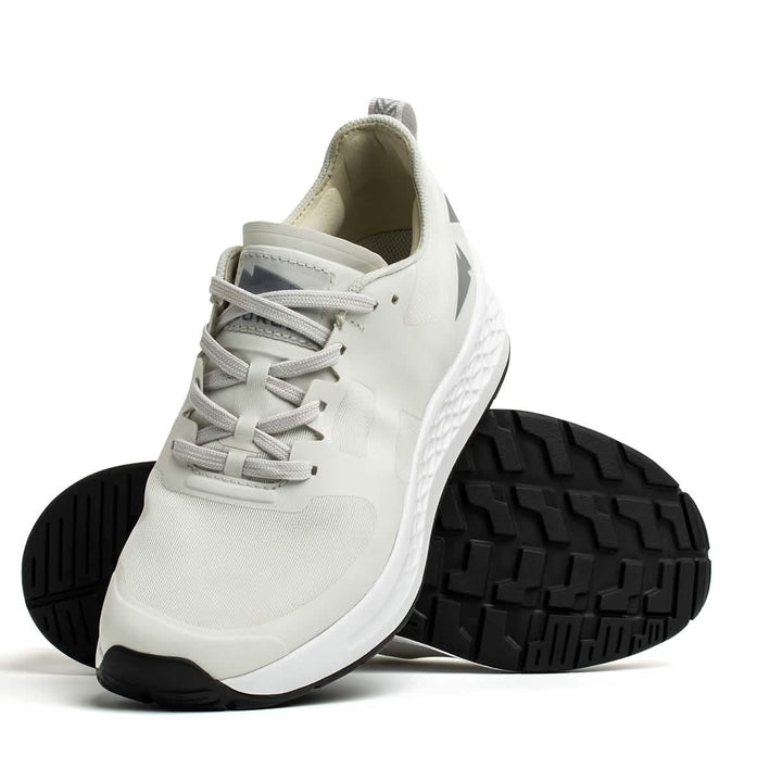 The GORUCK Men's Rough Runner in light grey and dark grey is featured against a pristine white background. This athletic shoe highlights its textured sole with gradient density and is positioned to emphasize both the top design and the tread pattern beneath.