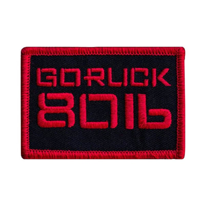 Introducing the Patch - Sandbag Weight by vendor-unknown: a rectangular design with a striking black background and red border, ideal for rucksacks. It showcases the embroidered text GORUCK 8016 in vibrant red and attaches easily using secure VELCRO strips.