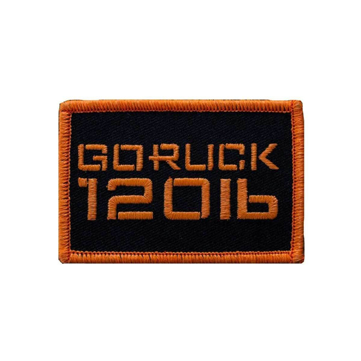 A rectangular patch labeled "Patch - Sandbag Weight" from vendor-unknown features an orange border and bold orange text on a black background, designed to attach seamlessly to rucksacks with VELCRO backing.