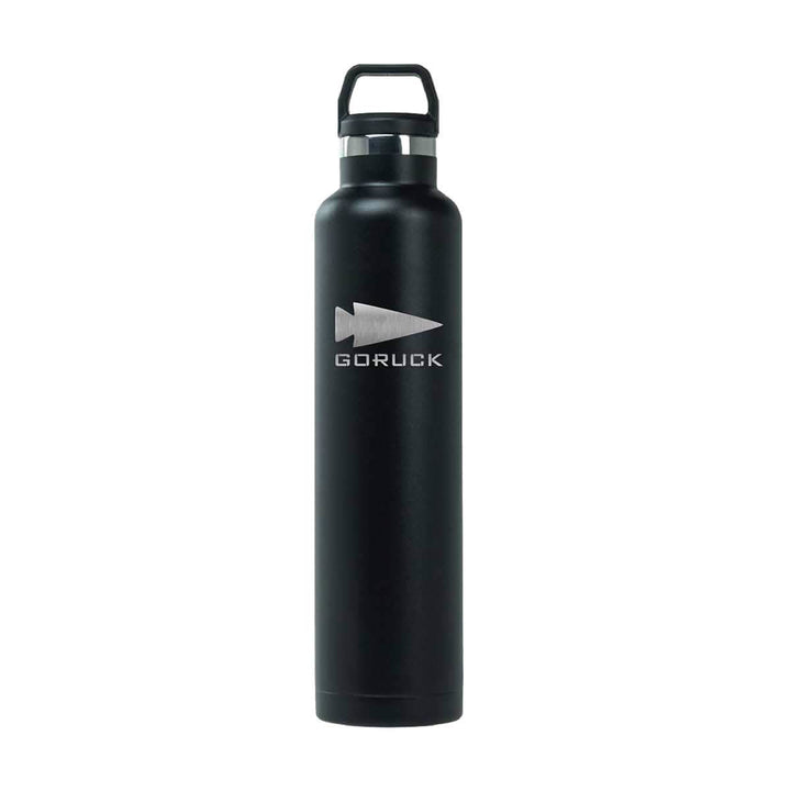 Introducing the GORUCK x RTIC Water Bottle, a tall and stylish black stainless steel bottle that showcases the GORUCK logo with an arrowhead design. This double wall insulated bottle features a secure cap with a handle for convenient carrying, offering quality comparable to RTIC bottles.