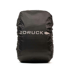 The Ruck Rain Cover from GORUCK features a black design with the brand name and arrow logo in white on the front. It is crafted from a lightweight, water-resistant material that fits snugly over your backpack against a plain white background.
