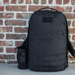 GORUCK black rucksack backpack with MOLLE webbing, set against a brick wall