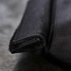 Close-up of a folded corner showcasing the textured black fabric made from durable 1000D CORDURA. The fine weave reveals intricate stitching details against a gray background, embodying resilience similar to GORUCK's Sandbags 2.0.