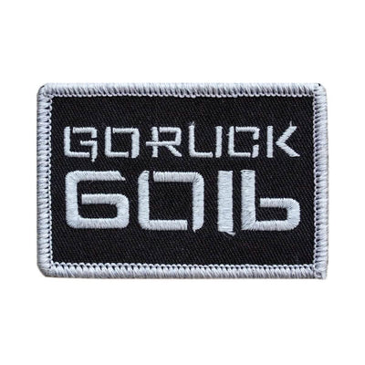 Product Description: The Patch - Sandbag Weight by vendor-unknown features a black rectangular design with a white border. The bold, stylized "GORUCK 6016" text is embroidered on the patch. It includes a VELCRO backing, making it ideal for attaching to rucksacks or sandbags, and it boasts a clean and minimalist aesthetic.