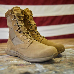 Pair of tan tactical GORUCK rucking boots on rustic wooden floor with American flag backdrop